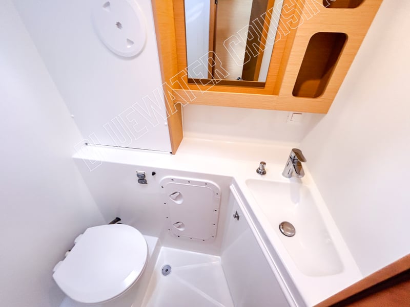 Compact guest head of a 2018 Lagoon 42-2 featuring modern fixtures, a marine toilet, and a sleek sink design.