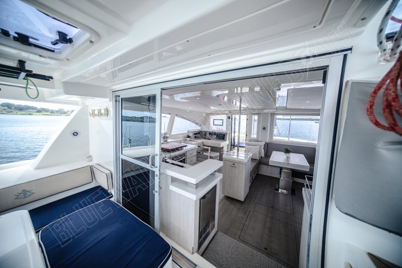 Interior view of a 2015 Leopard 48 catamaran showing the main salon with light wood cabinetry, modern galley, and dining area