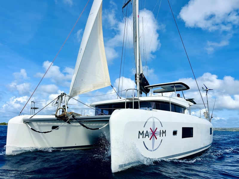 2018 Lagoon 42 catamaran sailing with full sails, showcasing twin hulls and spacious cockpit under a clear blue sky