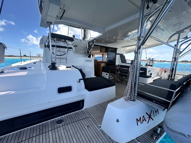 Teak-floored cockpit of a 2018 Lagoon 42 catamaran with bench seating, helm station, and open saloon access